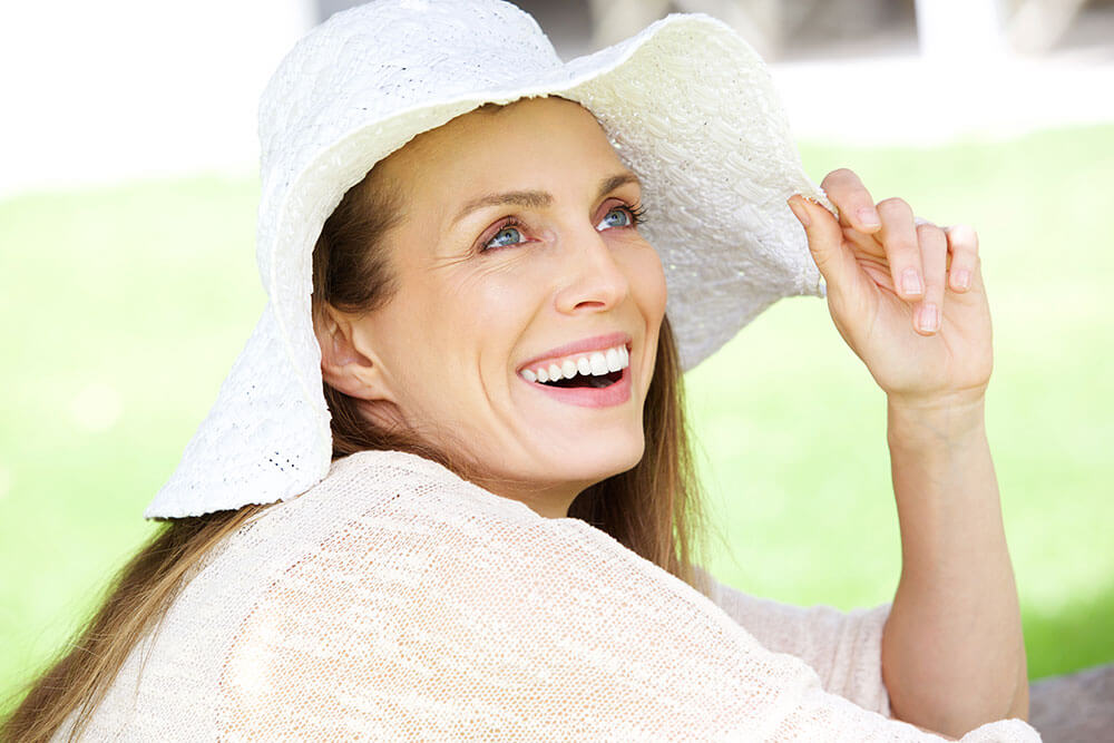 a middle aged woman smiling in a floppy sunhat