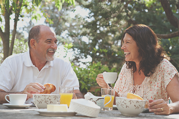 a set of middle aged people smiling over tea and treats