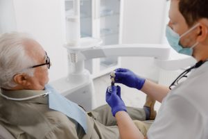 dentist showing older patient the parts of a dental implant