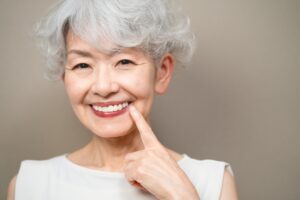 older woman smiling and pointing at teeth